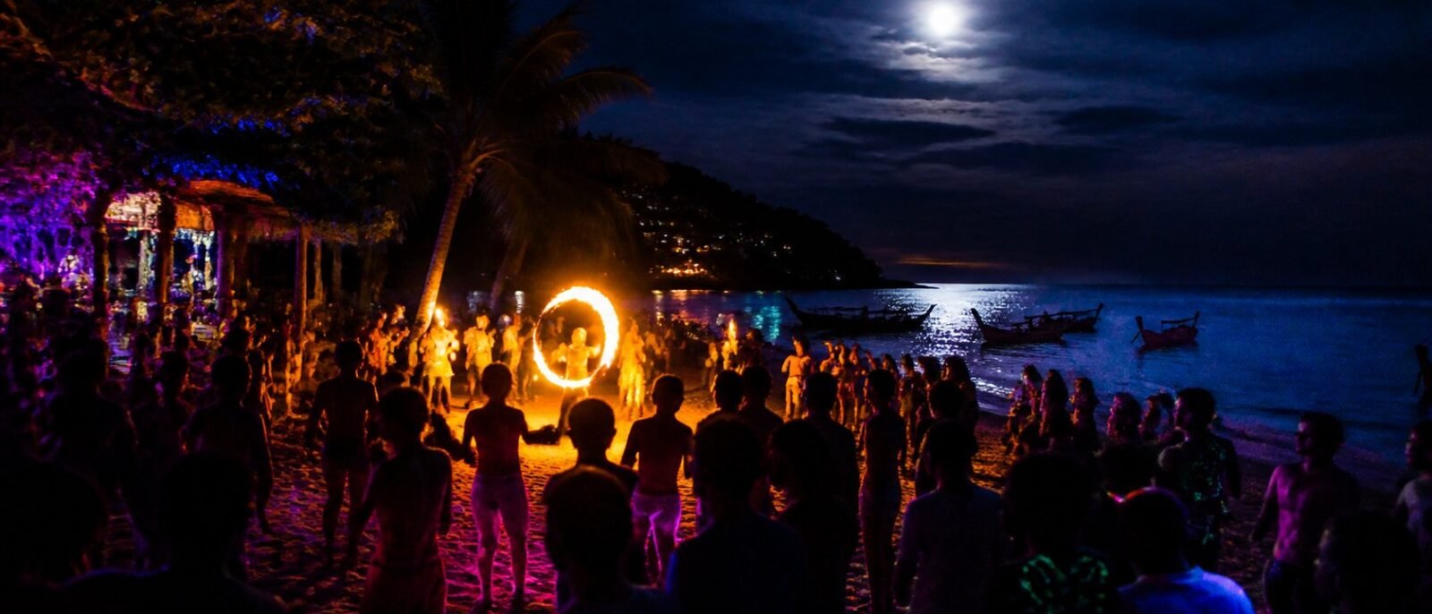 Beach party under a full moon on a Thai island with a fire dancer