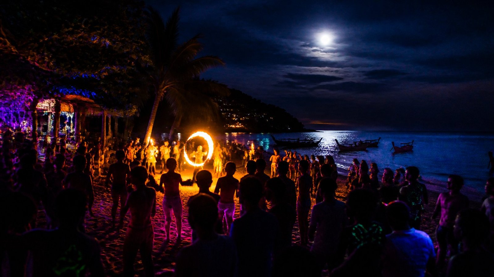 Beach party under a full moon on a Thai island with a fire dancer