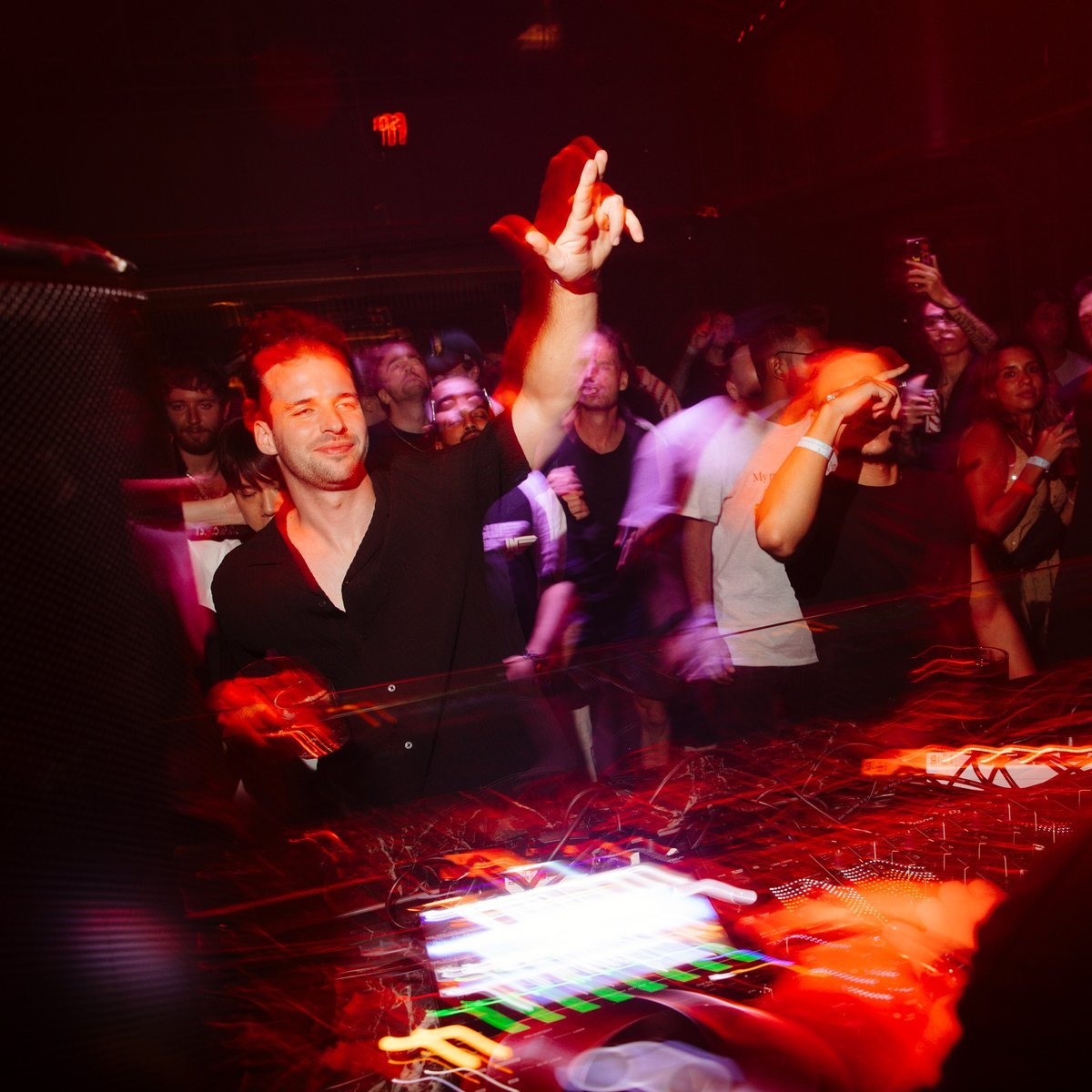 Crowd at the DJ booth during a techno night at Mustache Bangkok